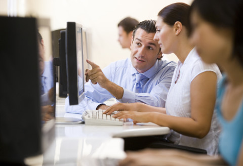 Man assisting woman in computer room